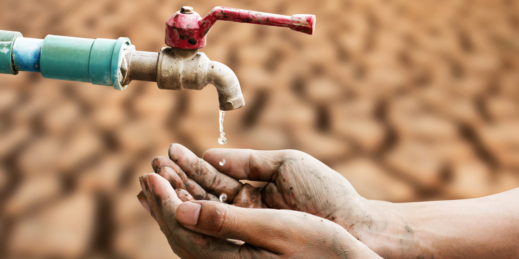 Hands catching last drops from a tap, illustrating severe water scarcity and drought.