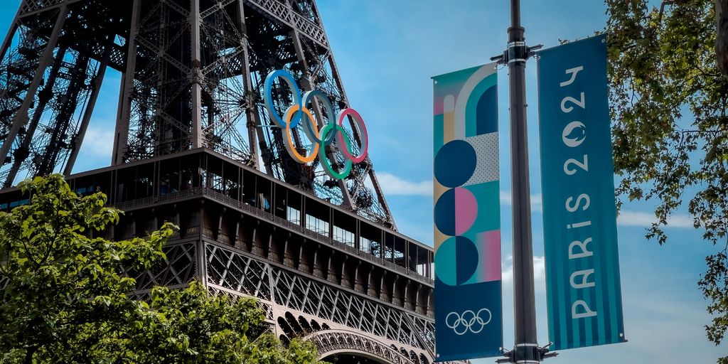 Paris 2024 Olympics banner and Eiffel Tower with Olympic rings, showcasing the iconic landmark and event preparations in Paris